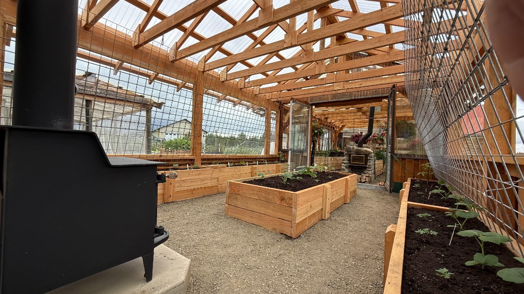 Interior of a greenhouse built with rough cut lumber framing and raised garden beds